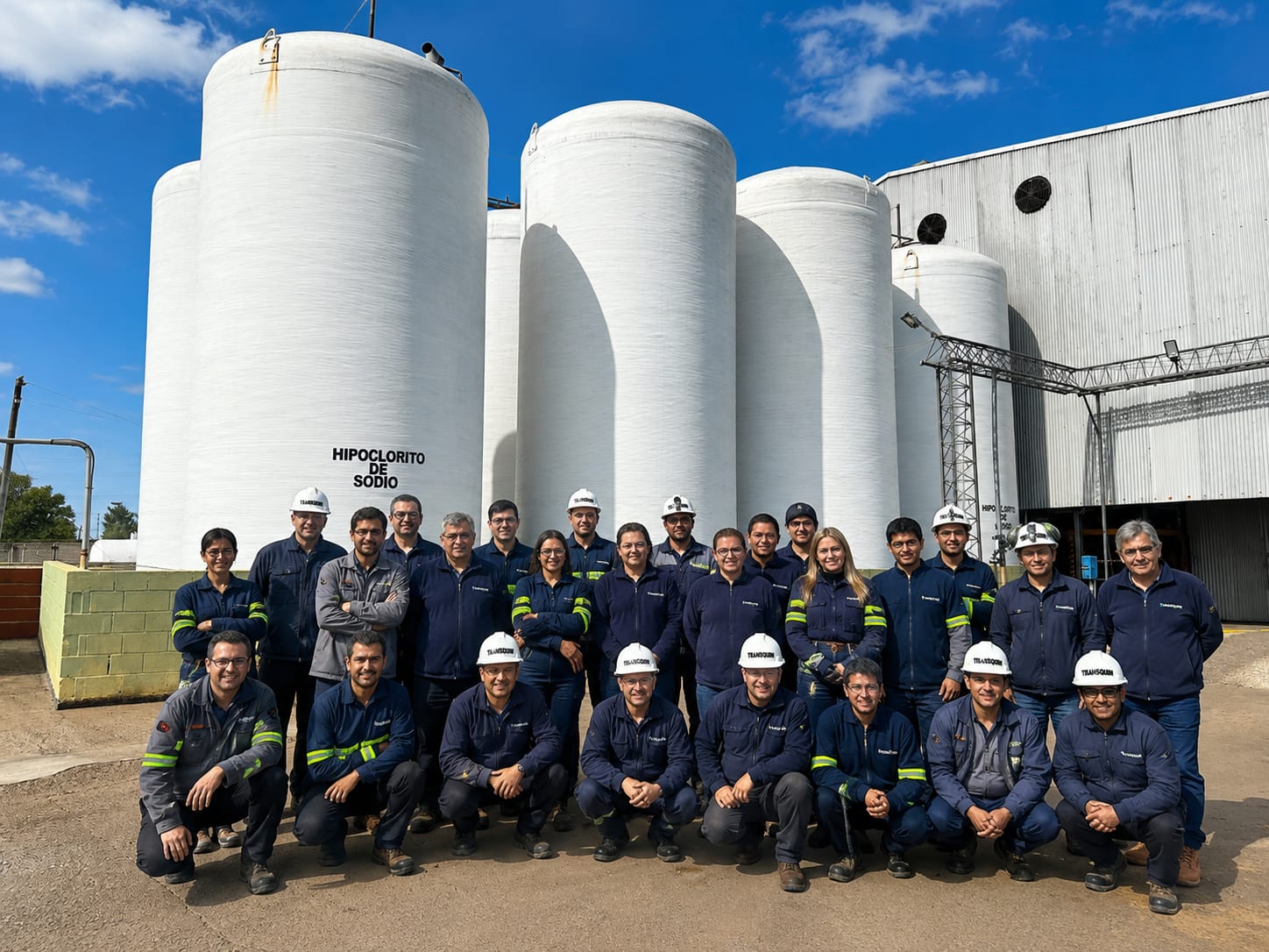 Equipo de Transquim con ropa de trabajo frente a los tanques de hipoclorito de sodio de la planta